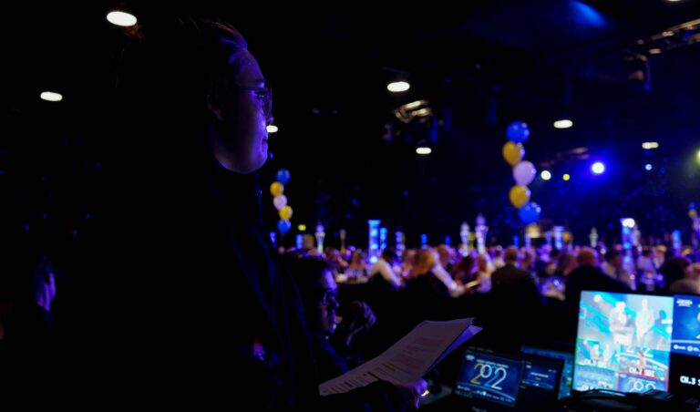 Image of project manager stood in the foreground with audience blurred in background